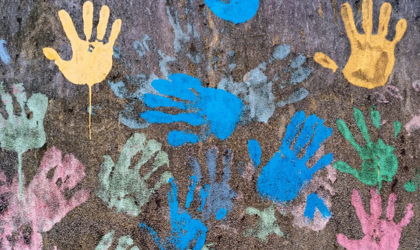 Dark background with colorful handprints symbolising interracial friendship